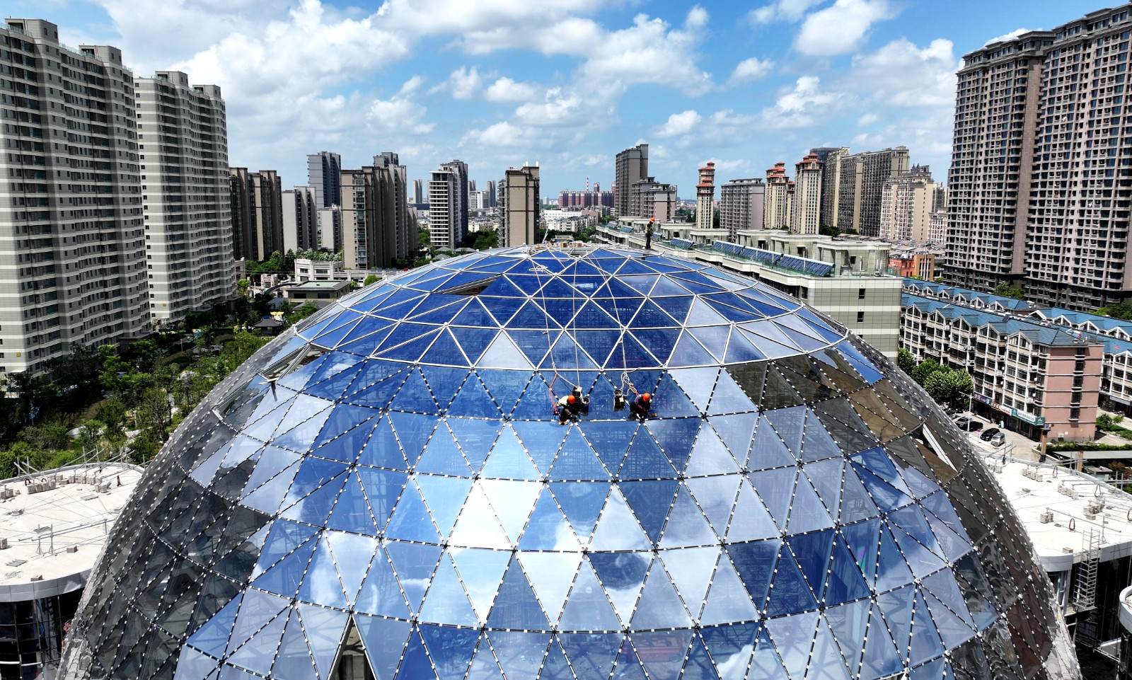 连日来，我市各重点项目建设者避开高温时段加紧施工，确保工程如期完工。图为施工人员在金镶玉商办综合体幕墙上忙碌。顾华夏 (5).JPG